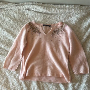 Rosa tröja med söta detaljer - Perfekt tröja när du inte vill sticka ut för mycket men ändå inte vara helt basic. En rosa tröja med jättefina detaljer!! Använd ett fåtal gånger. Säljer på grund av att jag vuxit ur den.