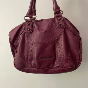 vinröd väska - från märket liebeskind har flera fack, en fläck insidan en av de (bild 4) finns axelrem, skickar med dustbag