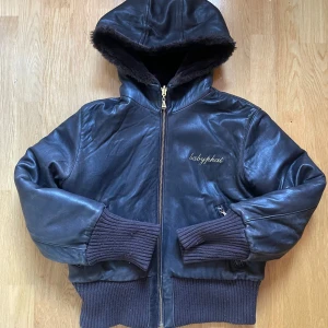 Baby Phat reversable jacka - Läderjacka och fluffjacka / fur i ett. Katt på ryggen och muddar som ger bra figur. Ut och in vändbar jacka från det populära 2000tals märket baby phat. Värnande och så mysig på höst och vinter! Strl L men har använts av mig som har S-M. Stor luva!