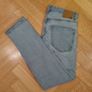 Ljusblå jeans  - Ett par ljusblå jeans. Tillverkad av 99% bomull och 1% elastan. Fickor fram och bak. Knäppning på framsidan med dragskedja och knapp. Bra skick förutom en lagning i grenen pga förslitning. Knappt synligt från utsidan. Slimmy fit. 