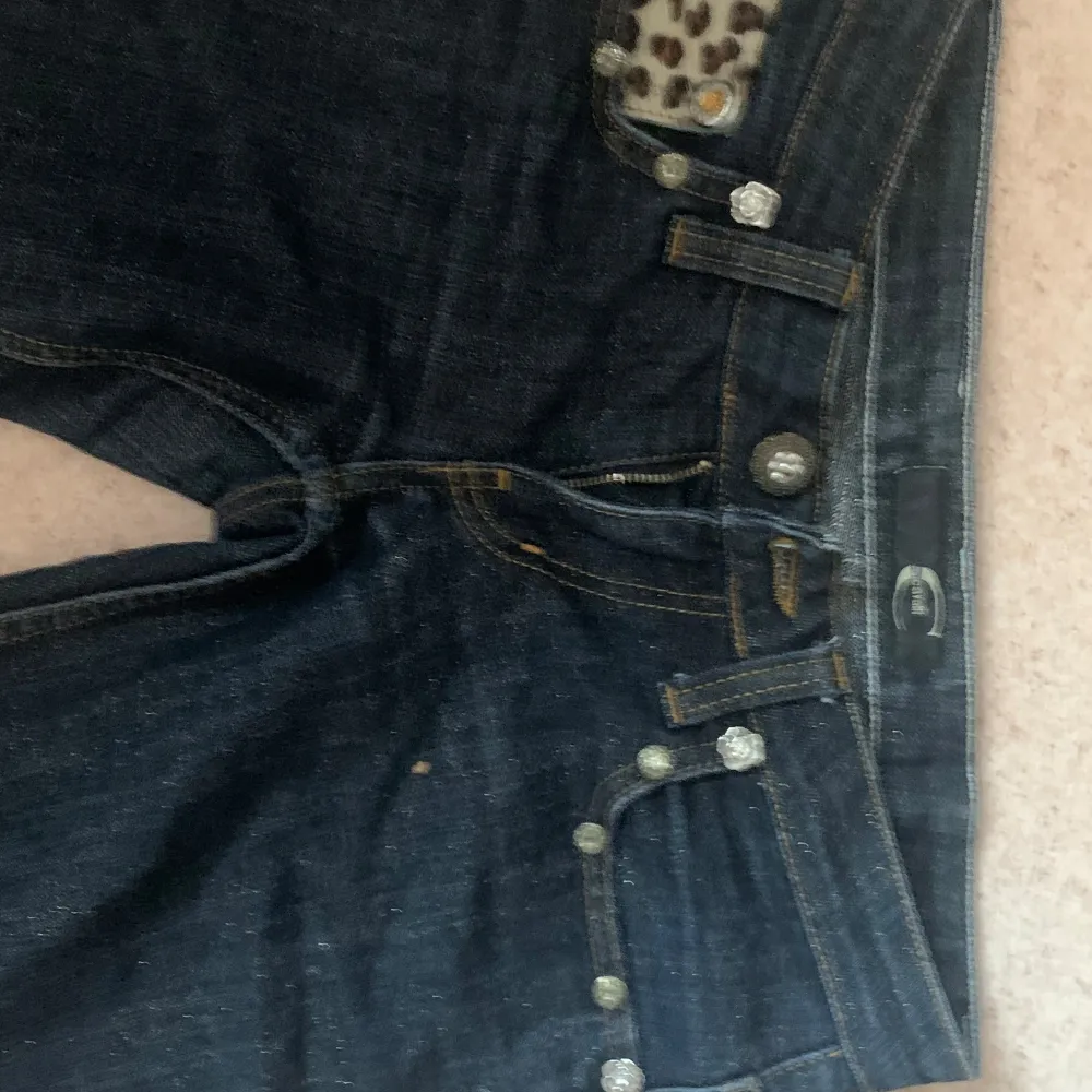 Säljer ett par mörkblå jeans med coola leopardmönstrade fickdetaljer och glittriga knappar. De har en tight passform och låg midja. De är äckta just cavalli. Storleken på lappen är 27. Midjemåttet är 37cm. Innerbenslängden är 72cm. Observera att hela jeansen är glittriga. Kan sänka priset vid snabbt köp! . Farkut & Housut.