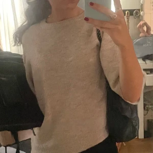 Beige stickad tröja från 157 - Mysig beige stickad tröja från 157 i storlek XS. Perfekt för kyliga dagar med sin mjuka och bekväma passform. Tröjan har trekvartsärmar och en rund halsringning. Passar både till vardags och lite finare tillfällen. Ett måste i garderoben för höst och vår!