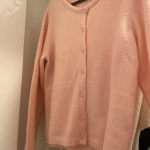Rosa kofta med knappar - Säljer en superfin rosa kofta i mjukt material. Den har långa ärmar och knappar hela vägen ner. Perfekt för både vår och höst när du vill ha något mysigt men ändå stilrent. Passar lika bra till jeans som till en klänning. 🧡