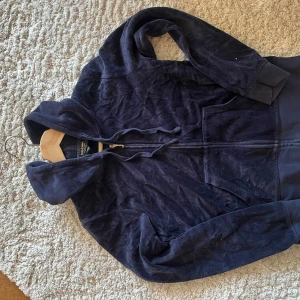 Mörkblå hoodie med dragkedja - Säljer en mörkblå hoodie i mjukt material med dragkedja framtill. Perfekt för kyliga dagar eller mysiga hemmakvällar. Den har en bekväm passform och en praktisk huva. Perfekt för höst och vår!