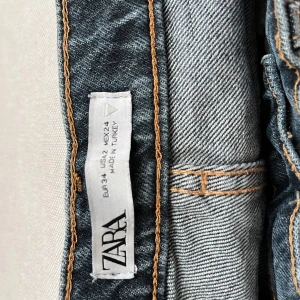 Blå jeans från Zara - Säljer ett par snygga blå jeans från Zara i storlek XS. De har en klassisk femficksdesign och knappar framtill. Perfekta för vardagsbruk och kan enkelt matchas med olika outfits. 💕