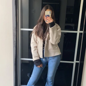 Beige kappa - Säljer en snygg kappa i mycket bra skick. Den har en klassisk design med knappar framtill och långa ärmar. Perfekt för höst och vår, och funkar perfekt till vardag. 