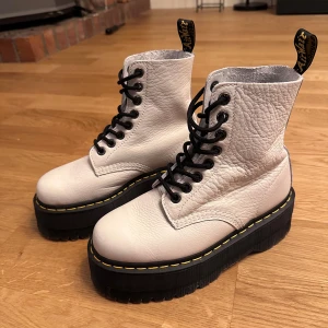 Vita boots med platåsula - Säljer ett par vita Dr. Martens boots i skinn med platåsula. De har svarta snören och den klassiska gula sömmen runt sulan. Perfekta för att ge lite edge till din outfit. Helt nya. 