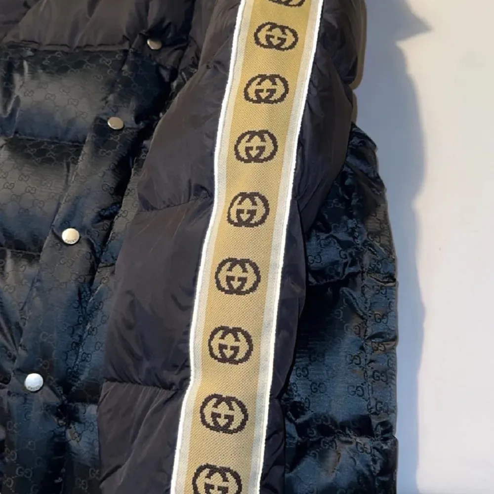 Säljer en svart pufferjacka från Gucci i mycket bra skick. Jackan har ett beige logotypband längs ärmarna. Perfekt för vintern med sin varma och stiliga design. Passar både till vardags och festliga tillfällen. Priset kan deskutiras . Jackor.