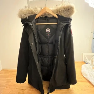 Svart vinterjacka med pälskrage - Säljer en svart vinterjacka från Canada Goose i mycket bra skick. Jackan har en mysig pälskrage och är perfekt för kalla vinterdagar. Den har långa ärmar och en dragkedja framtill. Supervarm och stilren! kvitto finns!