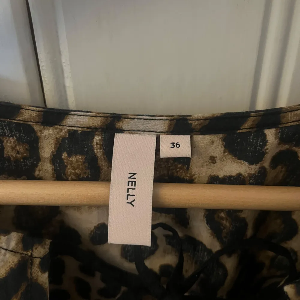 Säljer en supercool leopardmönstrad blus från Nelly. Den har korta ärmar och en snygg snörning framtill. Perfekt för en utekväll eller när du vill sticka ut lite extra. Blusen är i bra skick och redo för nya äventyr! 🐆✨. Toppar.