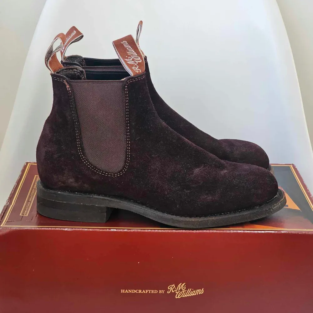 Säljer ett par snygga bruna mocka boots från R.M. Williams i mycket bra skick. De har en klassisk design med elastiska paneler på sidorna för enkel på- och avtagning. Perfekta för höst och vinter, och de ger en stilren touch till vilken outfit som helst.. Skor.