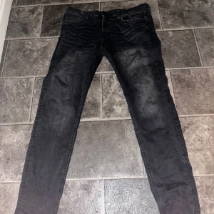 Svarta jeansbyxor - Säljer ett par svarta/gråa jeansbyxor i nytt skick. De har en slim passform och är perfekta för både vardag och fest. Klassisk design med fem fickor och knappgylf. Passar till det mesta i garderoben! Säljer då de int passar mig längre och har ingen användning för dem. Priset kan diskuteras