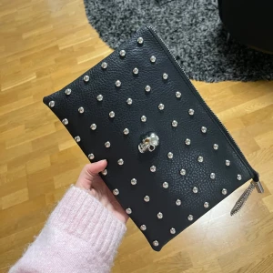 Svart kuvertväska med nitar - Snygg svart kuvertväska med coola silverfärgade nitar och en dödskalle-detalj på framsidan. Pris kan diskuteras 🤎