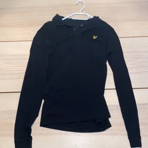 Svart pikétröja från Lyle & Scott - Säljer en stilren svart pikétröja från Lyle & Scott i mycket bra skick. I storlek XS