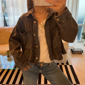 Grå jeansjacka från Zara - Säljer en snygg grå jeansjacka från Zara i storlek L. Jackan har en cool, sliten look med råa kanter och stora fickor fram. Jag brukar ha S som referens 
