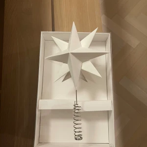 Vit julstjärna i papp från dbkd - Säljer en elegant vit julstjärna i papp, perfekt för att toppa granen. Den har en stilren design med en spiralfot för enkel montering. Stjärnan är ny och kommer i originalförpackning. Perfekt för att ge julgranen en klassisk och stilren look. 🎄✨