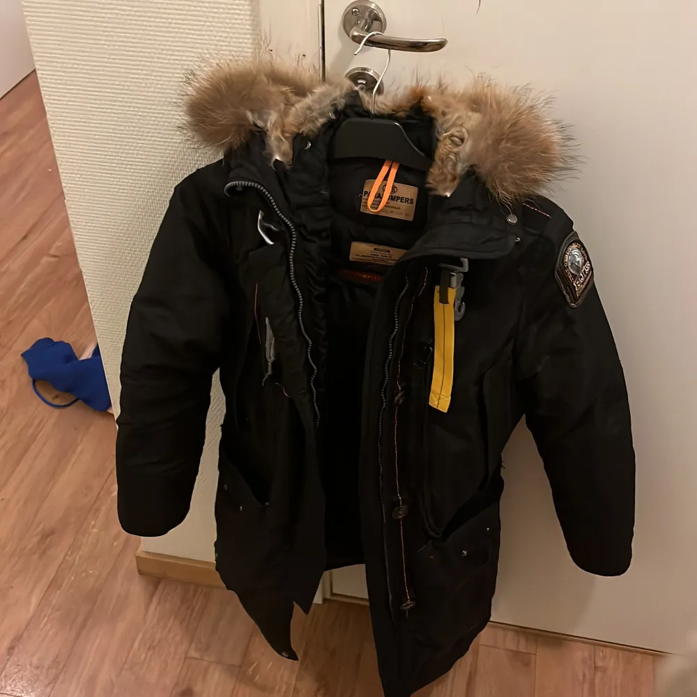 Säljer en svart Parajumpers vinterjacka i medium. Den har en mysig pälsfodrad huva och flera praktiska fickor. Jackan är perfekt för kalla vinterdagar. Dock finns det ett hål i luvan som går att sy igen om man vill och dragkedjan funkar inte. Jackor.