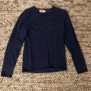 Mörkblå långärmad tröja från J. Crew - Säljer en stilren mörkblå långärmad tröja från J. Crew. Perfekt för både vardag och lite finare tillfällen. Tröjan har en liten bröstficka som ger en extra detalj. Materialet känns mjukt och bekvämt mot huden. Passar perfekt till jeans eller chinos!