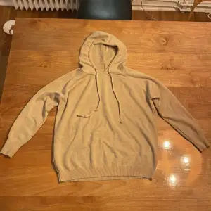 Säljer en mysig beige hoodie i merinoull . Perfekt för kyliga dagar. Den har långa ärmar och en praktisk huva med dragsko. Passar både till vardags och avslappnade tillfällen. Den är helt oanvänd.