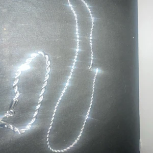 Silverfärgat halsband och armband - Säljer ett snyggt set med ett silverfärgat halsband och matchande armband. Båda har en vriden design som ger en cool och modern look. Perfekt för att piffa upp vilken outfit som helst, oavsett om det är till vardags eller fest. Halsbandet och armbandet är i mycket bra skick och redo att bäras!