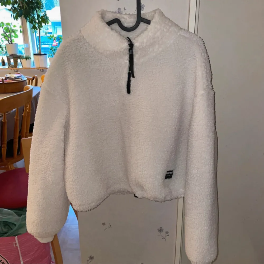 Aldrig använd, Mysig vit fleece tröja från Divided i storlek M. Perfekt för kalla dagar med sin fluffiga och varma design. Tröjan har en halv dragkedja framtill och en hög krage för extra värme. Den är i mycket bra skick och redo att hålla dig varm i vinter! ❄️. Tröjor & Koftor.