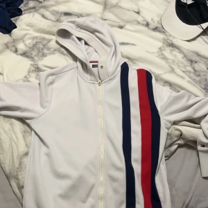 Vit huvtröja med ränder - Säljer en snygg vit huvtröja från Tommy Hilfiger med dragkedja. Priset sänks ifall man skriver, väldigt bra skick på den 