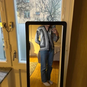 Svartvit mönstrad skjorta - Säljer en stilren svartvit skjorta med ett unikt geometriskt mönster. Skjortan har långa ärmar och knappar framtill. Perfekt för både vardag och festliga tillfällen. Passar bra till jeans eller kjol för en chic look!