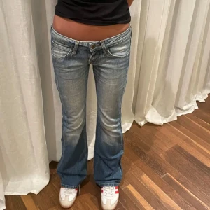 Blå bootcut jeans - Säljer ett par snygga blå bootcut jeans i bra skick. De har en låg midja och klassisk femficksdesign med knappar och dragkedja. Perfekta för en avslappnad stil och passar till både vardag och fest. Sköna och trendiga! Köpta på Plick av Jeansarkivet men var passade tyvärr inte, (Jeanssrkivets bilder) Midjemått: 38x2 cm Innerbenslängd: 83 cm