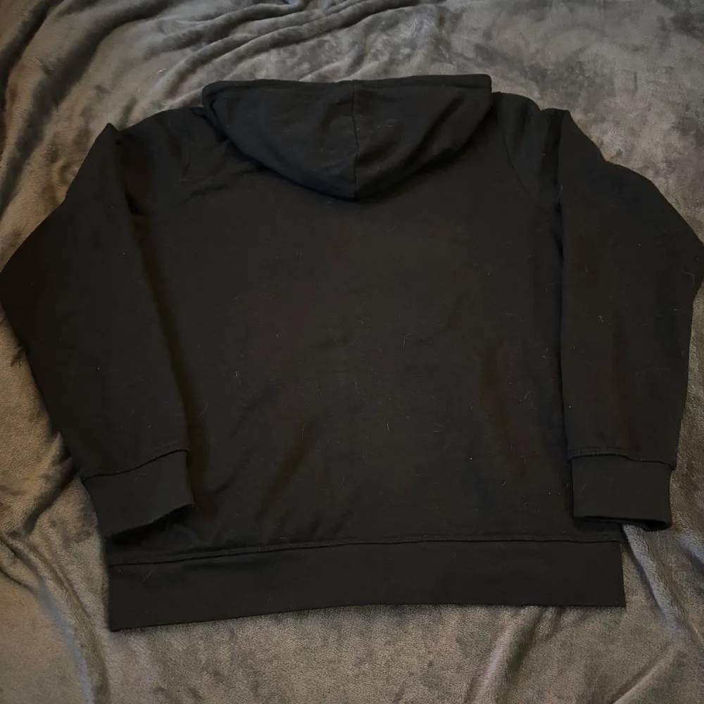 Säljer en svart hoodie från Kappa i storlek medium men är mer som S. Den har en dragkedja framtill och en klassisk Kappa-logga på bröstet. Perfekt för höst och vinter, med en skön passform och huva för extra värme. Perfekt för vardagsbruk eller chill dagar hemma.. Tröjor & Koftor.