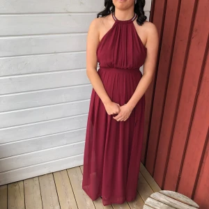 Vinröd långklänning - Säljer denna balklänning. Vinröd med diamanter runt hals och öppen rygg. Är uppsydd någon cm då jag är 158 cm lång, men hade klackar på mig. Köpare står för frakt ❤️