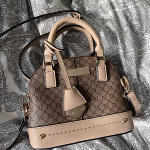 River Island Väska - Säljer en superfin oanvänd handväska från River island i beige och brunt. Justerbar axelrem och dragkedja upptill. 