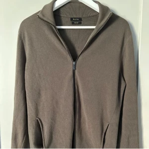Brun tröja med dragkedja från Massimo Dutti - Säljer en stilren ”olivgrön” tröja från Massimo Dutti i mycket bra skick. Den har en praktisk dragkedja framtill och är perfekt för både höst och vår. Tröjan är långärmad och har en bekväm passform. Perfekt för en casual look eller att klä upp med en skjorta under. Passar även medium! (Lånade bilder)