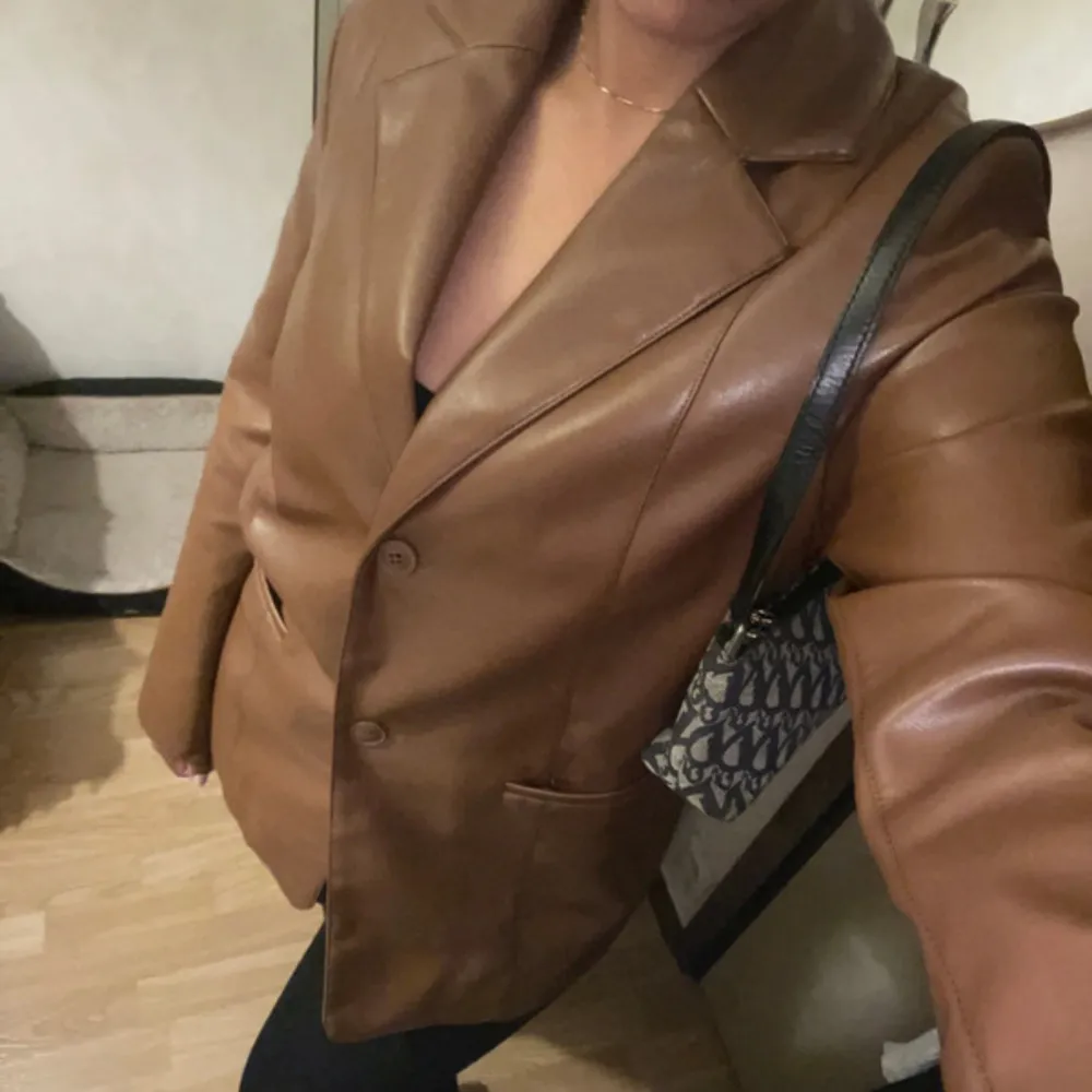 Säljer en snygg brun skinnjacka i mycket bra skick. Den har en klassisk kavajstil med knappar framtill och en normal passform. Perfekt för höst och vår, och funkar lika bra till vardags som till fest. Jackan har långa ärmar och en stilren design som gör den lätt att matcha med olika outfits.. Takit.