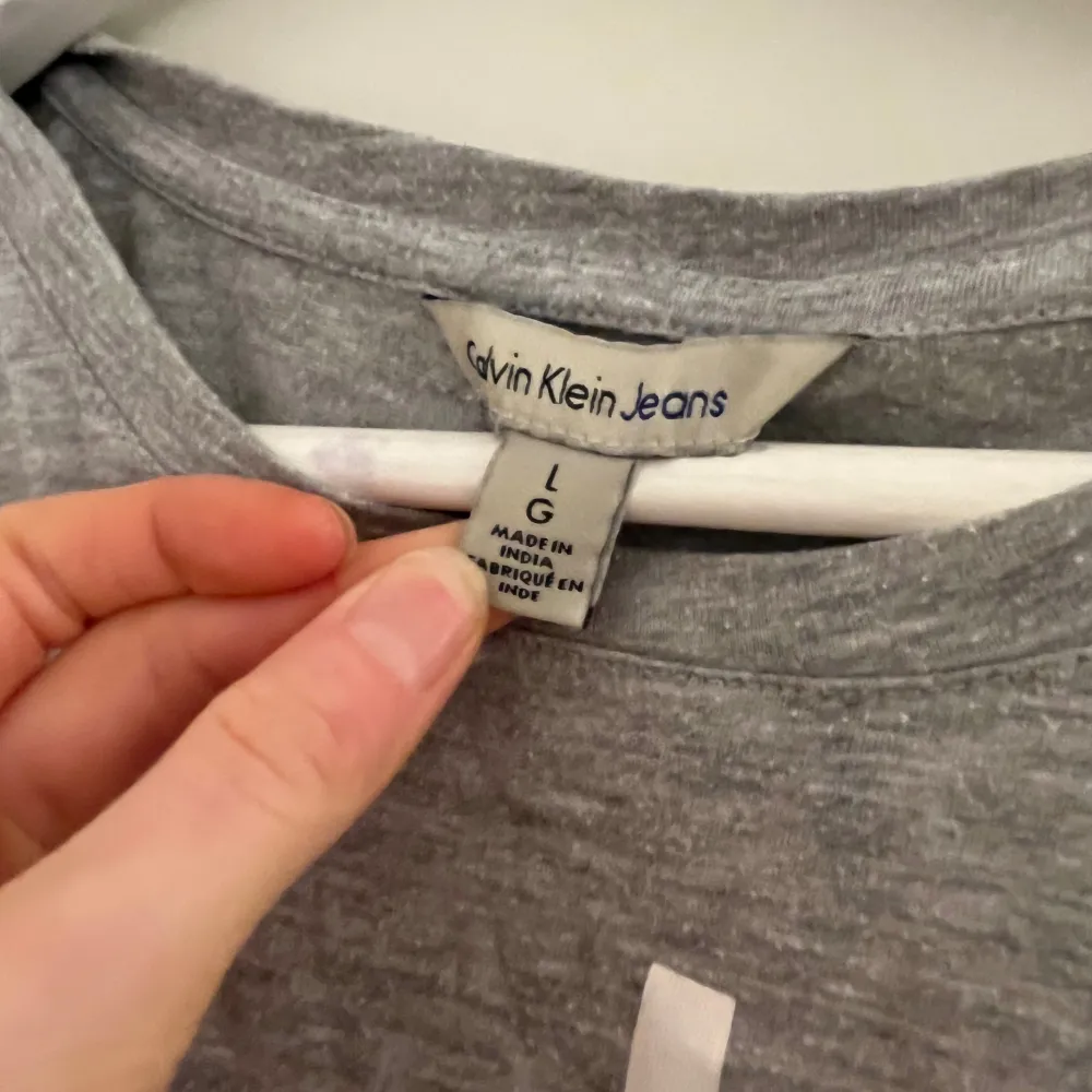 Säljer en snygg grå t-shirt från Calvin Klein Jeans i storlek L. Den har en klassisk design med korta ärmar och det ikoniska CK-logotypen tryckt på framsidan. Perfekt för en avslappnad stil eller som basplagg i garderoben.. T-shirts.