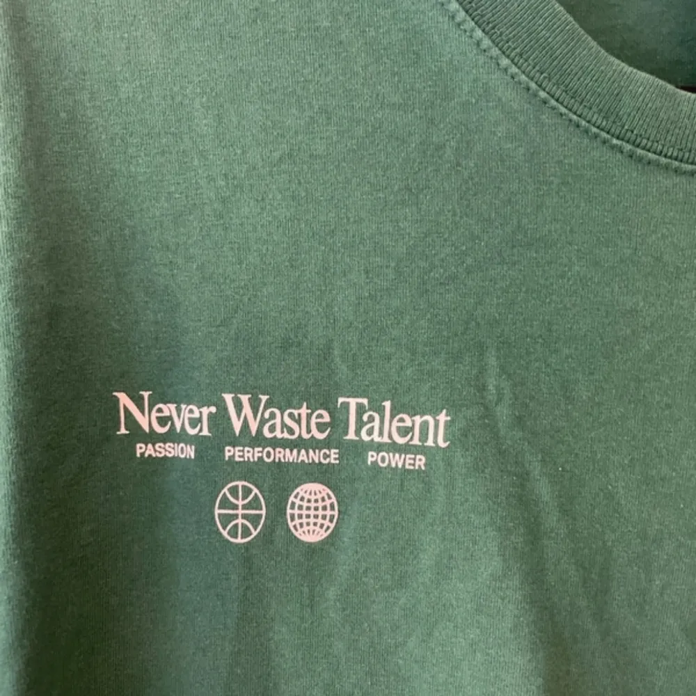 Säljer en grön t-shirt från H&M i storlek L. Den har texten 'Never Waste Talent' tryckt både fram och bak. T-shirten är i bomull och har en avslappnad passform, perfekt för vardagsbruk. Den är kortärmad och i mycket bra skick.. T-shirts.