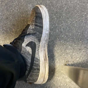 Nike sneakers i svart och grått. Kommer tvätta dem innan jag skickar den - Säljer ett par Nike sneakers i svart och grått med ett coolt mönster. De har snörning och en vit sula som ger en snygg kontrast. Perfekta för både vardag och träning. Skorna är i bra skick och redo för nya äventyr!