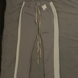 Unika EPTM. herr trackpants med omvända dragkedjor - Dessa EPTM. (känt märke i USA grundat i LA) byxor är gjorda av 100 % polyester, vilket säkerställer hållbarhet och komfort. Funkar bra som unisex och med en perfekt passform (inte för tighta och inte för breda) samt har även omvända dragkedjor nertill och långa snören vilket är väldigt unikt och coolt. Oanvända tags medföljer, storlek S passar även M, nypris 900kr säljes för 399kr. 👍