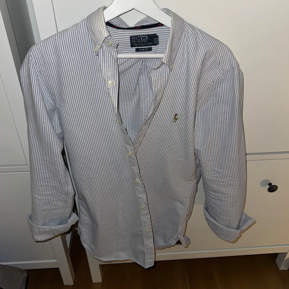 Säljer en stilren och klassisk randig skjorta från Polo Ralph Lauren. Skjortan är i bomull och har en snygg vit och blå färgkombination. Storlek S men passar till och med M🤩 Perfekt för både vardag och fest! 🕺. Skjortor.