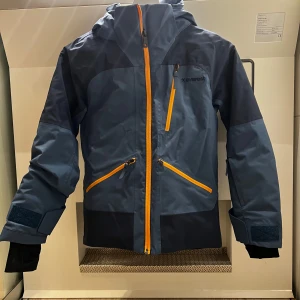  Jättefin skidjacka från Everest storlek 134 cm  - Storlek 134  J Lex Softshell Jacket från Everest är en vind- och vattentät juniorjacka med utmärkt andasfunktion, idealisk som skidjacka eller vinterjacka för andra utomhusaktiviteter. Jackan är varmt vadderad, tillverkad i ett mjukt material och har tejpade vattentäta sömmar. Den har en avtagbar justerbar huva och extra hög krage som är mjukt borstad på insidan för att ge extra skydd och värme. Jackan har ett snölås i midjan som effektivt hindrar vind och snö från att komma in underifrån. 