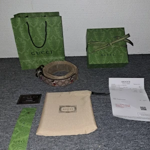 Gucci bälte - (OBS pris kan diskuteras vid snabb affär‼️) Säljer ett snyggt Mickey Mouse x Gucci bälte i mycket bra nyskick. Den har det klassiska GG Supreme-mönstret i beige och brunt med Mickey Mouse detaljer i rött och svart. Bältet kommer med originalförpackning och kvitto. Perfekt för att ge din outfit en lyxig touch :)