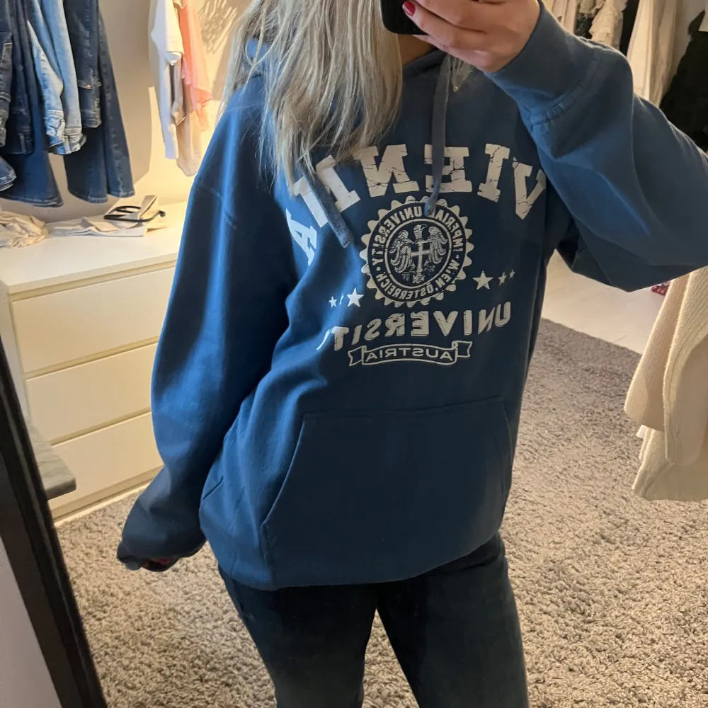 Säljer en snygg blå hoodie med vitt tryck framtill. Den har en stor ficka på magen och en bekväm passform. Köpt i Wien!!!💙💙. Hoodies.