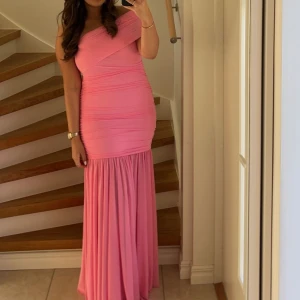 Rosa långklänning - Säljer en superfin rosa långklänning med oneshoulder-design. Klänningen har en tight passform upptill och faller vackert ner mot golvet, finns en slits på baksidan. Perfekt för fest eller bal! 💖