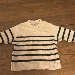 Randig ribbad tröja från lager 157 - Säljer en superfin randig tröja från 157 i storlek M. Den är beige med svarta ränder och har en ribbad struktur som ger en snygg look. Perfekt för både höst och vår! Tröjan har långa ärmar och en bekväm passform som sitter tajt så tröjan borde passa folk som har S och XS också. Passar perfekt till jeans eller kjol för en avslappnad stil.