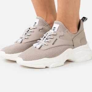 Beige sneakers med vit sula - Snygga och bekväma beige sneakers med vit sula. De har en stickad ovandel och snörning framtill. Perfekta för vardagsbruk och ger en sportig look. Passar bra till både jeans och träningskläder.