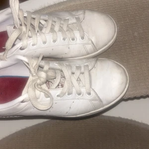 Stan smith skor 💕 - Säljer ett par vita stan smith sneakers i bra skick. De har en cool röd och svart leopard mönster på hälen och klassisk snörning. Perfekta för vardagsbruk och ger en stilren look. Passar till det mesta i garderoben!💕💕