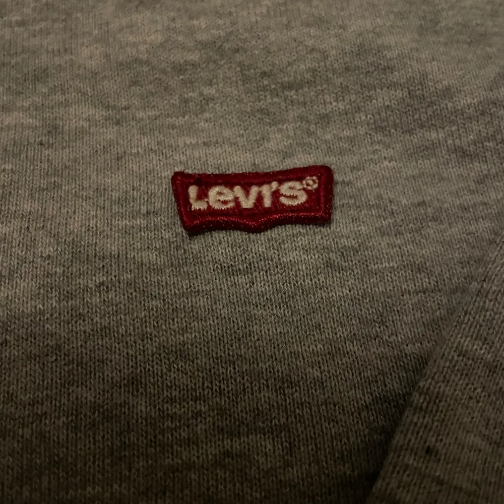 Säljer en snygg och bekväm grå hoodie från Levis. Den har en klassisk design med en liten röd Levis logga på bröstet. Perfekt för en avslappnad stil och passar till det mesta. Huvan har dragsko och tröjan är i mjukt material. Skriv vid minsta lilla fundering✍️😀✅. Tröjor & Koftor.