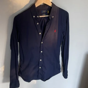 Mörkblå skjorta från Polo Ralph Lauren - Säljer en snygg mörkblå skjorta från ralph lauren i storlek S. Den är knappt använd och har inga defekter. Nypris ligger runt 1500, mitt pris är endast 699 om ni har frågor är det bara att skriva.