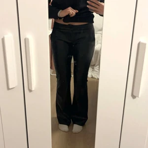 Svarta skinnbyxor - Säljer ett par snygga svarta skinnbyxor i bootcut-stil. Har aldrig använt dom så kände dom kunde göra nytta hos någon annan. De är lågmidjade och har en tight passform upptill. Perfekta för en kväll ute eller en cool vardagslook. Byxorna är i nytt skick. Jag är 1,70 o dom når ner till golvet. Nypris 379kr