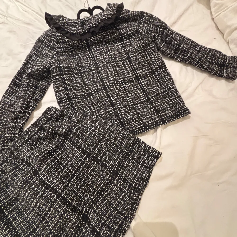 Säljer en superfin svartvit rutig jacka med en väldigt fin kjol till. Den har en elegant och klassisk stil, perfekt för höst och vår. Jackan är långärmad och har en snygg passform som passar både till vardags och fest. Kjolen sitter väldigt fin!!  Perfekt för dig som vill ha något unikt i garderoben! Även väldigt bra julklappstips!! (MAN FÅR MED BÅDE TRÖJAN OCH KJOLEN) . Takit.