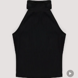Svart ribbad halterneck topp - Säljer min svarta ribbade halterneck topp. Den är ärmlös och har en hög krage. Toppen är croppad och passar perfekt till de mesta.
